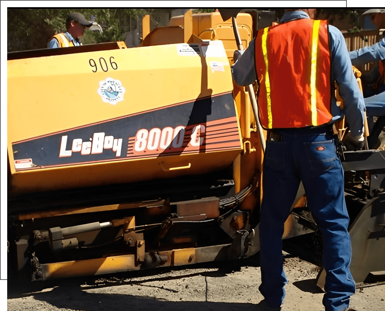 Workers operating asphalt paving machine